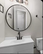 Durham bathroom after renovation, with a round mirror and modern vanity